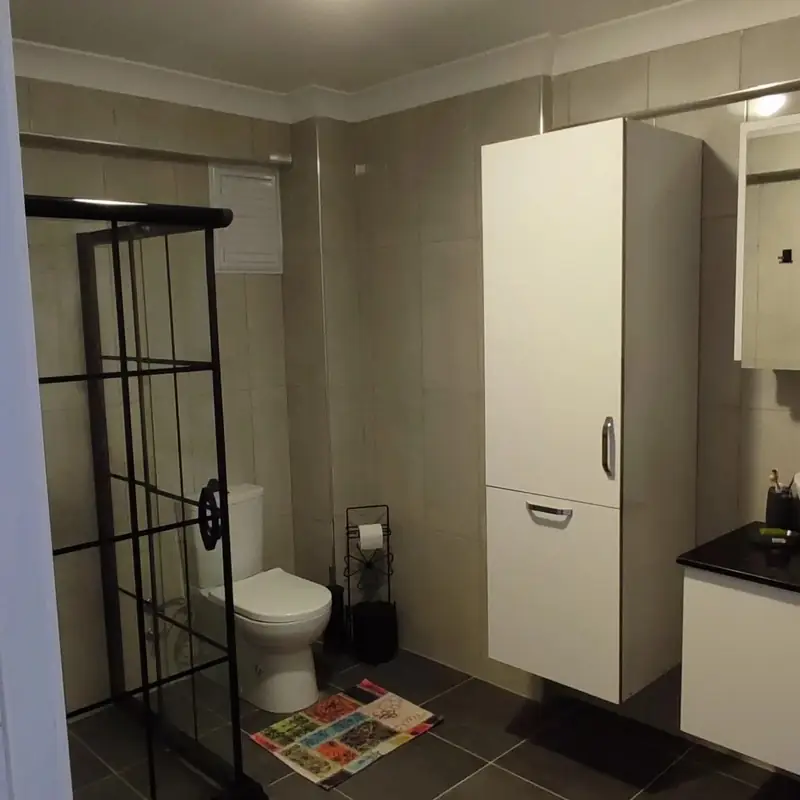 Duşakabin yanında beyaz banyo boy dolabı
